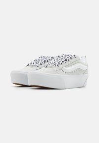 Sneakers platform grigio chiaro, in materiale scamosciato, con lacci decorati da stelle nere e strisce bianche sui lati. Suola in gomma testurizzata, fodera in rete.