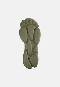 Suola di scarpa in gomma verde con superficie strutturata, caratterizzata da più segmenti arrotondati e scanalature per la trazione. Bordo liscio e dettagli minimi.
