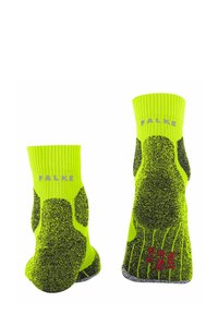 Jasnozielone skarpetki neonowe z prążkowanymi mankietami, z czarnymi teksturowanymi wzorami na podeszwach i czerwonymi akcentami oraz logo marki „FALKE”.