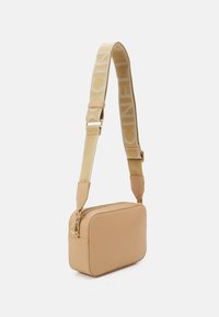 Beżowa skórzana torba crossbody z szerokim regulowanym paskiem, ozdobiona plecionym beżowo-kremowym wzorem oraz złotym zamkiem.