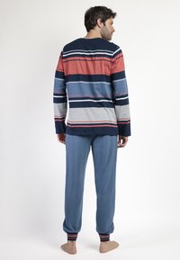 Top de manga larga a rayas en colores azul marino, gris y coral, combinado con pantalones azul claro con puños acanalados y un ajuste relajado.