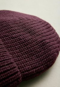 Knit purple beanie with a textured ribbed pattern, featuring a soft, thick material and a rounded top shape.