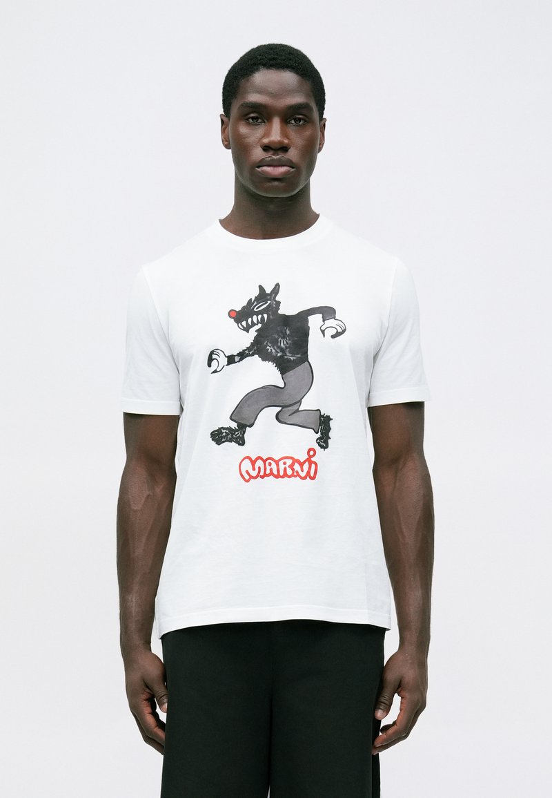 Balta kokvilnas T-krekls ar melnu karikatūras vilka grafiku un sarkaniem "Marni" burtiem apakšā. Īsas piedurknes un klasiskas piegriezuma dizains.