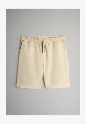 Beige Shorts aus weichem Stoff mit elastichem Bund und verstellbarem Zugband; verfügen über zwei Seitentaschen.