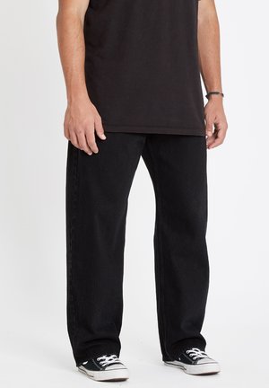 Svarte denimbukser med rett ben-design, med en enkel tekstur og subtil søm. Kombinert med svart-hvite sneakers.