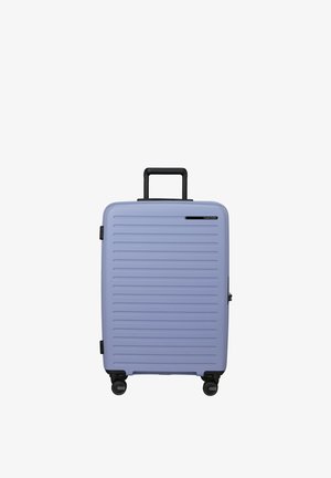Light purple hard-shell suitcase with horizontal ridges, black telescopic handle, and four spinner wheels.