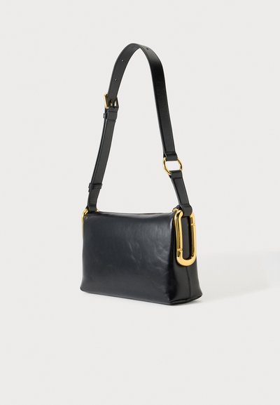 Sac à épaule en cuir noir avec sangle réglable et grandes boucles métalliques dorées de chaque côté.