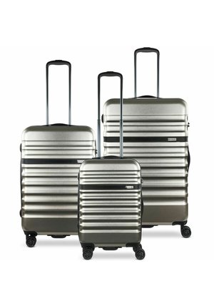 Set of three hard-shell suitcases in silver with horizontal ridges, retractable handles, and black accents. Features four wheels for mobility.