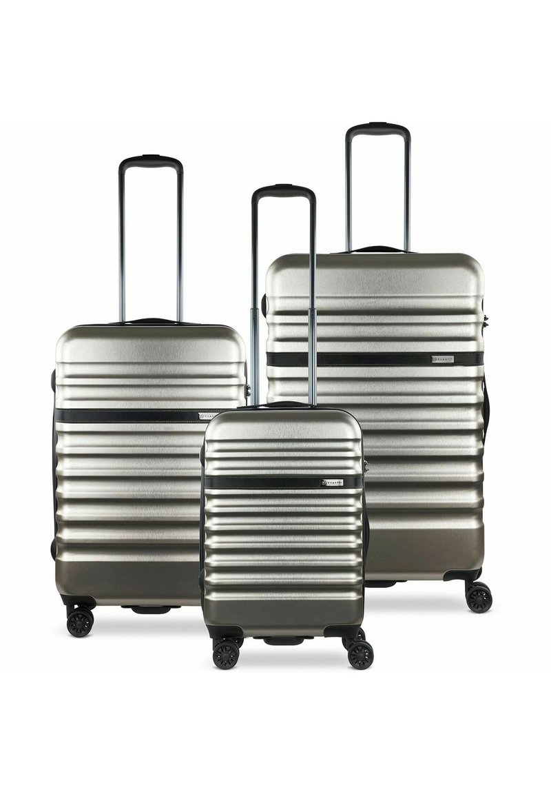 Set di tre valigie rigide in argento con righe orizzontali, maniglie estensibili e accenti neri. Caratterizzate da quattro ruote per la mobilità.