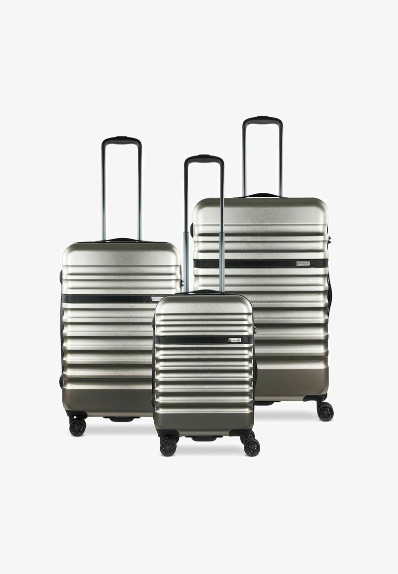 Set di tre valigie rigide in argento con righe orizzontali, maniglie estensibili e accenti neri. Caratterizzate da quattro ruote per la mobilità.