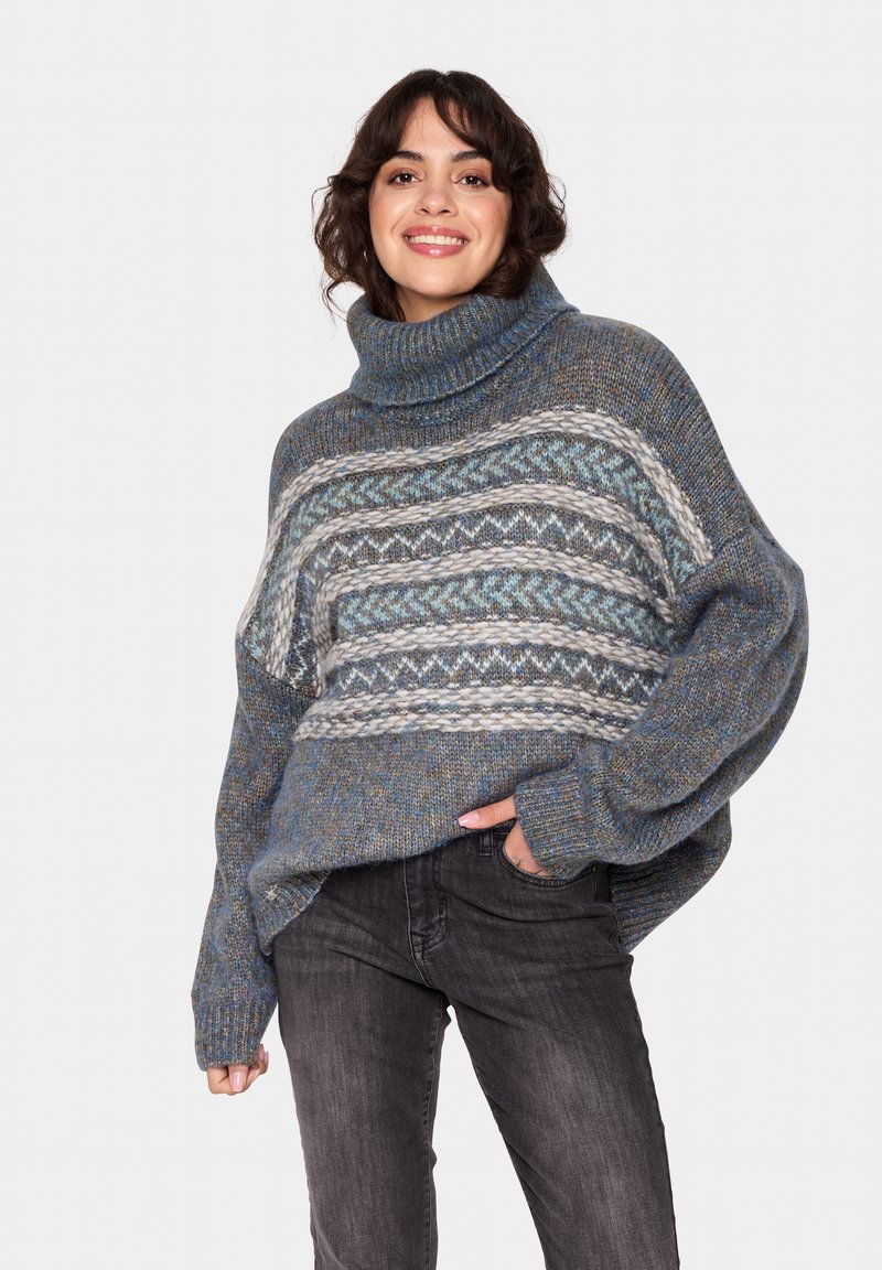 Pulover tricotat gros, cu un guler înalt, având modele albastre, gri și albe. Croi oversized, cu mansete și tiv râuri.
