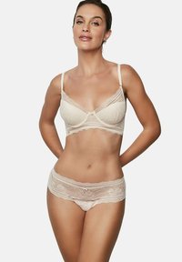 Ensemble en dentelle couleur beige clair comprenant un bralette avec des motifs floraux, des bretelles fines et des culottes assorties avec des bordures en dentelle et un bord festonné.
