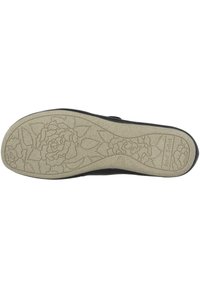 Black shoe sole with a textured cream base featuring a floral design. Smooth edges and an ergonomic shape for comfort.