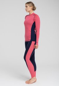 Langærmet sports top i pink med marineblå sidepaneler, parret med marineblå leggings med pink striber langs siderne. Blød tekstur, tætsiddende design.