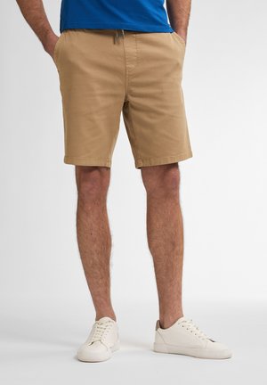 Khaki shorts with an elastic waistband, side pockets, and a straight cut. Worn with white sneakers, showcasing a casual summer look.