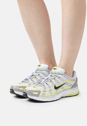 Buty do biegania marki Nike z siateczkową cholewką w kolorze szaro-żółtym z czarnymi akcentami, zaokrąglonym noskiem, amortyzowaną podeszwą i wiązaniem na sznurowadła.