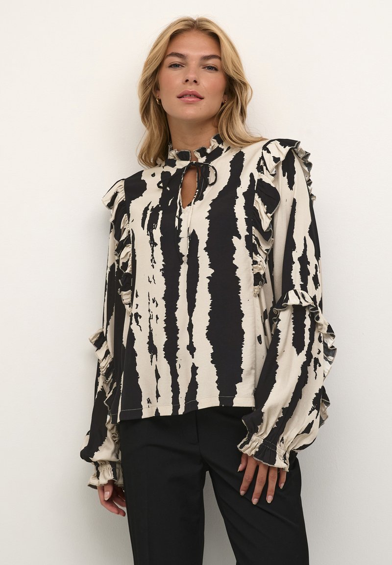 Blusa a righe nera e crema con maniche a balze, scollatura a occhiello e vestibilità rilassata. Realizzata in materiale leggero, presenta motivi audaci.