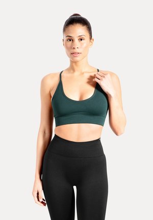 Donkergroene sportbeha met een ronde hals, verstelbare bandjes en een aangesloten pasvorm, gecombineerd met high-waisted zwarte leggings.