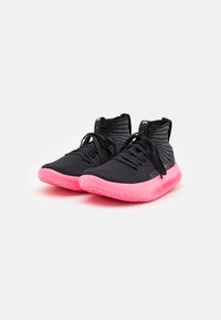 Zwarte sportieve schoenen met een gestructureerde bovenkant, een hoge enkelontwerp en een felroze zool. Voorzien van zwarte veters en accenten voor ondersteuning.