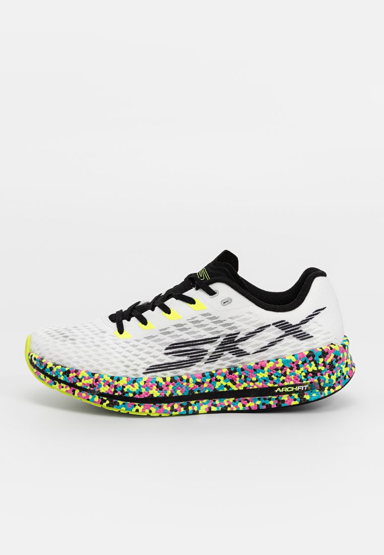 Baskets de course blanches avec une tige en maille texturée, accents noirs et une semelle mouchetée multicolore. Dotées d'un logo noir et de lacets jaunes.