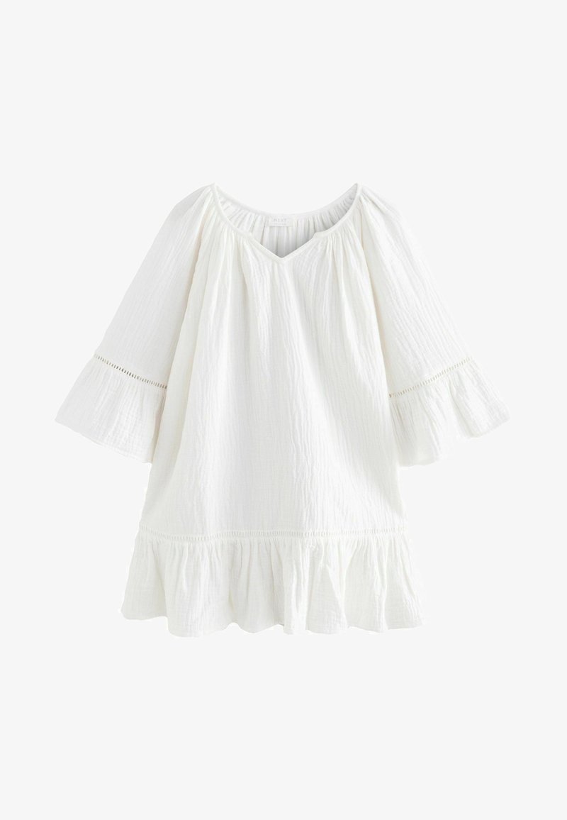 White cotton blouse with a V-neck, flared sleeves, and ruffle hem. Features textured fabric and subtle eyelet accents near sleeves.