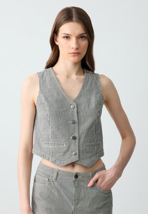 Débardeur court à rayures en tissu noir et blanc, avec un décolleté en V, cinq boutons et deux poches avant avec des accents contrastants.