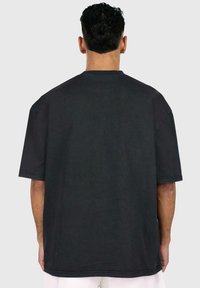 Camiseta oversized negra de manga corta y cuello redondo, con un acabado de tela texturizada y detalles de costura limpios y minimalistas.