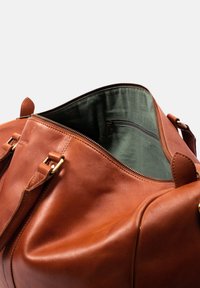 Braune Leder-Dufflebag mit glatter Oberfläche, ausgestattet mit goldenen Beschlägen und einem grünen Innenfutter. Enthält eine Reißverschlusstasche.