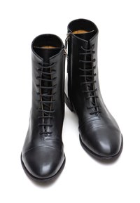 Stivali alla caviglia in pelle nera con punta affilata, dotati di lacci sul davanti e chiusura con zip laterale. Texture liscia e design elegante.