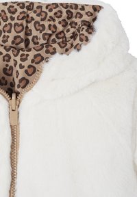 Weiße Kunstfelljacke mit einem beigen Reißverschluss. Das Innenfutter weist ein braunes Leopardenmuster auf. Die Kapuze ist weich und plüschig.