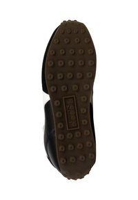 Suola di sneaker nera con un design testurizzato, caratterizzata da schemi circolari in rilievo e un materiale in gomma marrone. Logo visibile sulla suola.