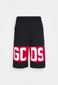 Shorts noirs avec larges bandes rouges près de l'ourlet, comportant de grandes lettres blanches "GCDS" sur les deux jambes et une poche arrière du côté droit.