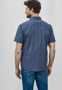Korte mouwen, knoopsluiting overhemd in marineblauw met een subtiel patroon van kleine driehoeken. Bevat een standaard kraag en een rechte zoom, gecombineerd met blauwe spijkerbroeken.
