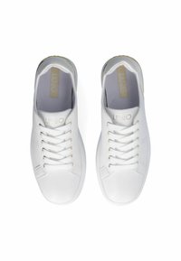 Zapatillas blancas con un acabado de cuero suave, puntera redondeada y cordones planos. Presentan un branding sutil y una suela texturizada para mayor agarre.