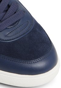 Zapatillas de cuero azul marino con parte superior de ante, cordones texturizados y suela de goma blanca. Acabado suave y blando con detalles de costura.