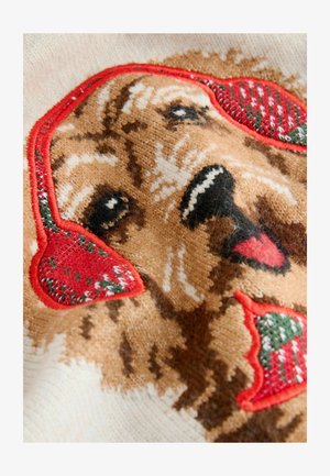 Kootud sviiter, millel on pruuni koera näo disain punaste kõrvaklappidega, millele on aktsentideks rohelised ja punased mustrid, kreemival taustal.