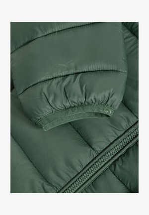Giacca imbottita verde con polsini a coste, fascia elastica con marchio e cerniera laterale. Il materiale appare liscio con una leggera lucentezza.