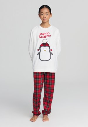Maglietta da pigiama bianca a maniche lunghe con grafica di un pinguino e testo rosso "Magic Season", abbinata a pantaloni di flanella a quadri rossi con dettagli neri.
