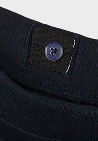 Tejido acanalado azul marino con textura elástica, que presenta un botón negro y detalles de costura en contraste en el interior.
