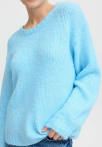 Maglione azzurro chiaro lavorato a maglia con colletto e polsini a coste, caratterizzato da una morbida e pelosa texture e da una vestibilità comoda.