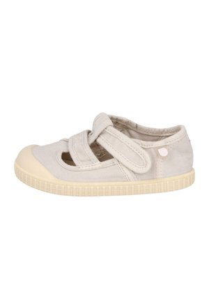 Zapato de lona para niño pequeño en beige claro con suela de goma y dos tiras ajustables de velcro en la parte superior.