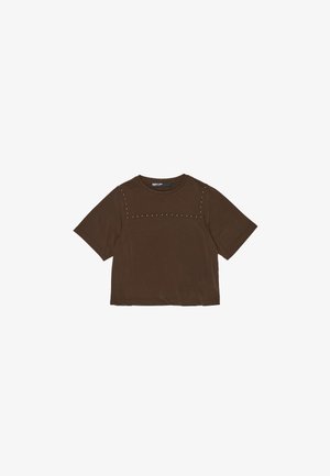 Bruine T-shirt met korte mouwen en een ronde hals, voorzien van een horizontale rij metalen studs langs het bovenste deel van de borst. Zachte stoftextuur.