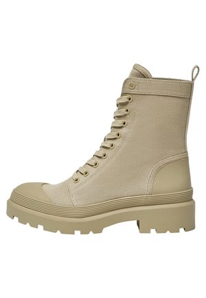 Botte haute en toile beige avec semelle épaisse en caoutchouc, lacets à l'avant, bout renforcé et languette à l'arrière.