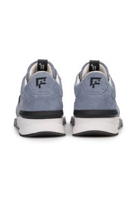 Blauwe suède sneakers met zwarte accenten, voorzien van een witte middenzool en hiel, met een logo aan de achterkant en een gestructureerd oppervlak.