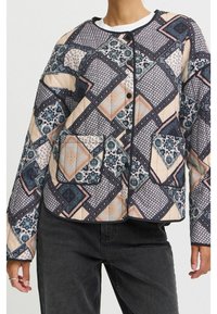 Quiltet jakke med patchwork-design i geometriske og blomsteragtige mønstre i marineblå, beige og teal. Inkluderer frontlommer og knaplukning.