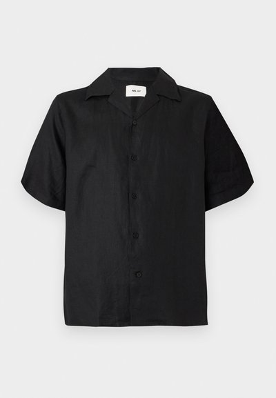 Chemise noire à manches courtes avec col camp, cinq boutons noirs sur le devant et une étiquette à l'intérieur de l'encolure.