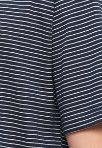 Υφασμα σε ναυτικό μπλε με λεπτές λευκές οριζόντιες ρίγες, κοντινή εικόνα ενός μανικιού σε κοντομάνικο πουκάμισο.