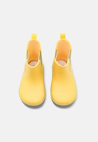 Dzelteni ūdensizturīgi apavi ar izgrieztiem sāniem, plakanām zolēm un aizmugurējām cilpām vieglai uzlikšanai. Gluda tekstūra ar kontrastējošām pelēkām apakšzolēm.