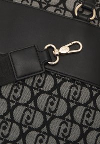 Sac noir et gris avec un textile à motifs, des accents en cuir et un fermoir en métal doré. Remarquable pour son design géométrique.