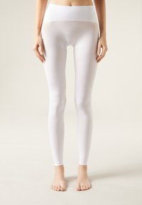 Hvide leggings med høj talje, glat tekstur og strækbart materiale, designet til at sidde tæt fra talje til ankel.